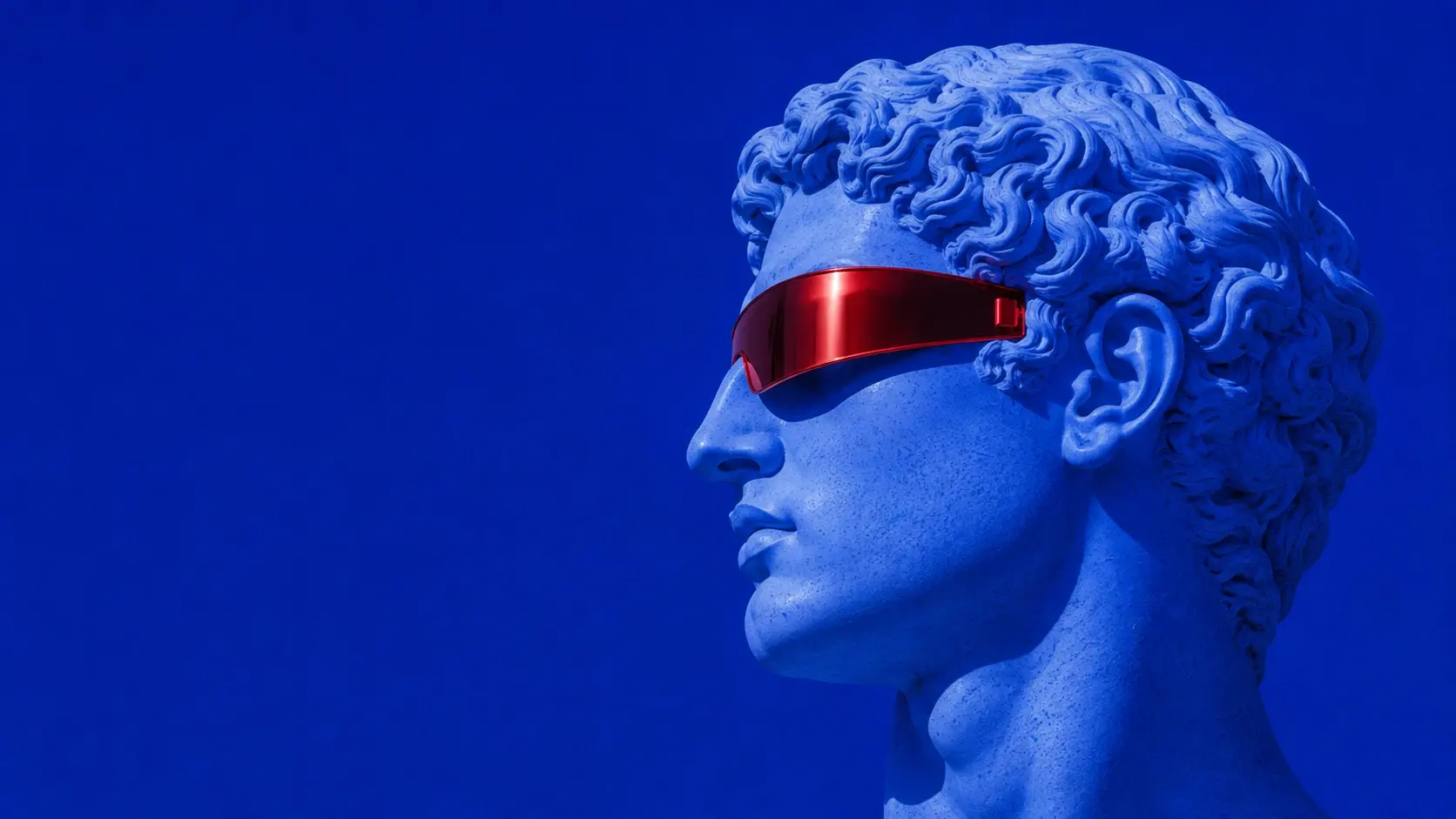 Wide 16:9 hero image, a perfectly sculpted classical male head in side profile occupying the right half of the frame, pale marble transformed into luminous icy blue with deep cobalt shadows, smooth ancient sculpture anatomy contrasted with an unusual futuristic chrome-red visor covering one eye, tiny red geometric detail near the temple, completely flat saturated ultramarine background, tactile stone pores and fine engraved texture, analog grain, subtle halftone dots, slightly distressed screen-print finish, sharp graphic silhouette, surreal fashion campaign aesthetic, restrained palette of blue, white and one vivid red accent, enormous empty blue space on the left for headline and UI, no text.