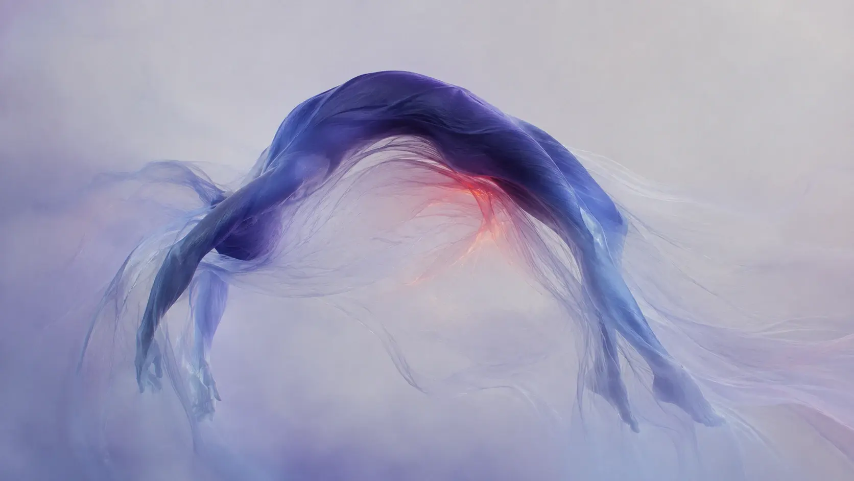 Wide 16:9 surreal editorial artwork, an abstract human-like silhouette suspended in an impossible horizontal arch, the upper body forming a thick sweeping crescent while elongated arms extend outward and dissolve into hundreds of hair-thin filaments, head bent downward and completely featureless, lower body disappearing into a soft translucent haze, enormous negative space beneath the arch, the form appearing simultaneously human and organic sculpture, dense #343850 indigo concentrated along the upper arc, transitioning into #8C92B2 dusty periwinkle across the surrounding fibers, #F2F2F3 luminous mist filling the background, warm #FFC39A light glowing softly through the hollow center, a restrained pinpoint of #FF7A18 orange at one internal crease, #0A0A0C barely perceptible in the deepest fold, thousands of individually visible fine strands, delicate translucent membranes, soft backlighting, subtle bloom, low saturation, analog film grain, quiet surrealism, premium contemporary art photography, no identifiable person, no clothing, no objects, no text.